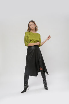 Serie of studio photos of female model in silk green blouse and black leather midi skirt