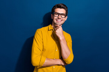 Photo portrait of handsome young guy touch chin thoughtful specs dressed stylish yellow outfit isolated on dark blue color background
