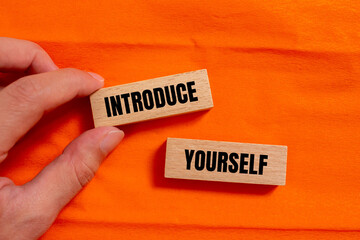 Introduce yourself words written on wooden blocks with orange background. Conceptual symbol. Copy space.
