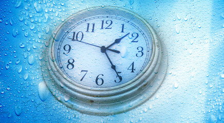 close up abstract raindrops and clock face over blue background