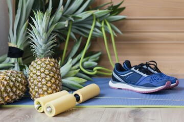 pineapple and sports shoes with a resistance band on a yoga mat
