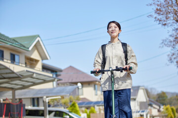 住宅街を電動キックボードで移動する日本人の女性