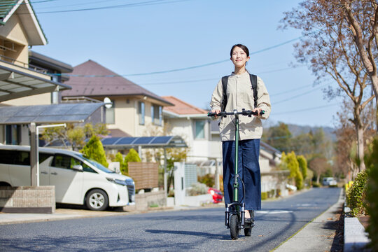 住宅街を電動キックボードで移動する日本人の女性