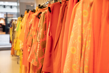 different models orange blouses in second hand store grouped in the same color