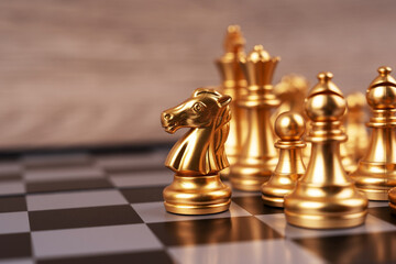 Motivational business and management concept. Golden chess pieces placed on a chessboard. Blurred...