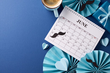 Reflective Father's Day beginnings: top view composition with June calendar, cup of coffee, paper fans and gift box, set against blue background, perfect for greeting message for Father's Day - Powered by Adobe