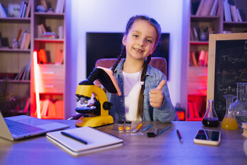 Caucasian child in casual wear studies by doing science in the evening at home. Portrait of smiling...