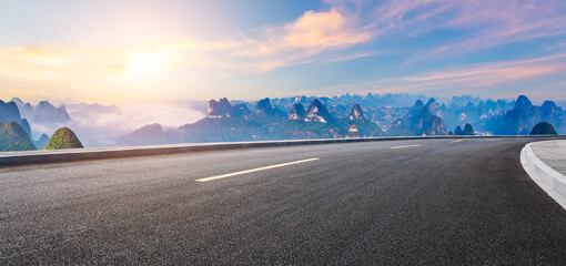 Asphalt highway road and green mountain with sky clouds natural landscape at sunrise. Panoramic view.