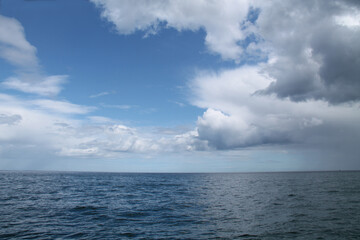 Fototapeta na wymiar Blue Sky and White Clouds Over an Open Ocean Sea.