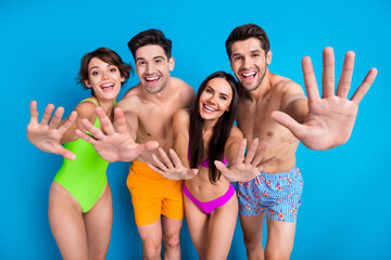Photo of four positive cheerful people dressed swimsuits showing you palms say hello in pool at...