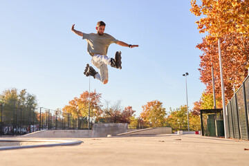 young male roller skater jumping and doing a trick with his inline skates.