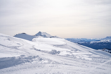 Serene snow-covered mountain landscape under a soft sky. - 773101484