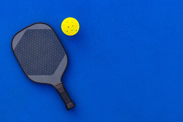 Pickleball tennis racket on the court. Blue background with copy space. Sport court and ball.