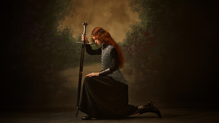 Pensive warrior princess, woman kneeling with sword, in contemplative pose against vintage...