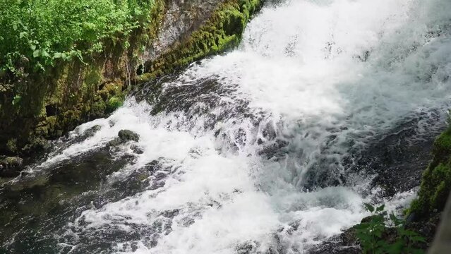 Footage of a rapid stream over rocks coming from waterfall in forest
