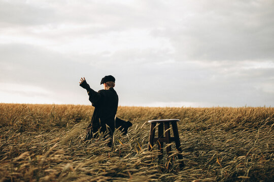 a village boy in a cap and jacket, 9 years old, runs in a wheat field.