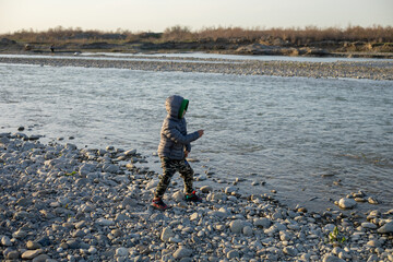 A young boy is playing in the water near a rocky shore