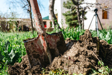 A shovel is sitting in the dirt next to a camera