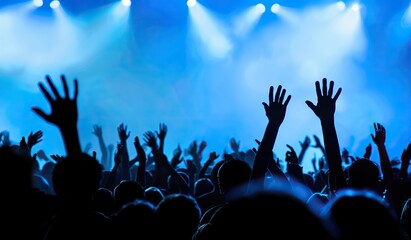 Silhouettes of a crowd with raised hands at a concert illuminated by stage lights. The concept of a...