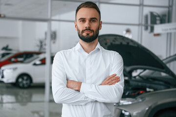 Portrait of beautiful man. Worker in formal clothes is in the auto salon