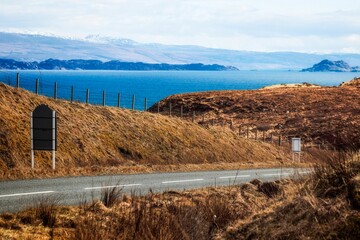 Scenic rural landscape with a long country road near a lake in Isle of Skye, Scotland, UK