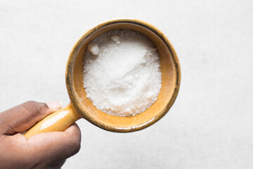 A bowl of white sugar, top view of granulated sugar in a brown bowl
