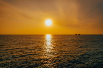 Obraz premium Majestic view of the sun setting over a serene ocean with a ship sailing in the background