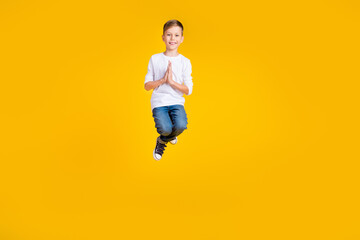 Obraz premium Full length photo of cute funny kid dressed white shirt jumping high praying empty space isolated yellow color background