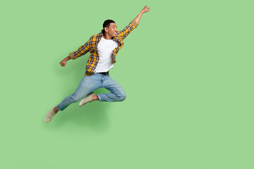 Full length profile portrait of excited crazy person raise arm fist jump fly empty space isolated on green color background - obrazy, fototapety, plakaty