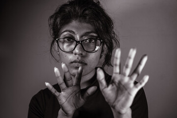 A woman with glasses is holding her hands up in a gesture of defiance - obrazy, fototapety, plakaty