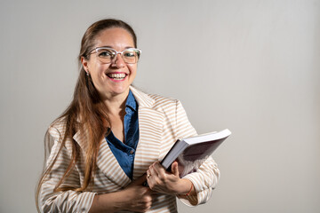 Mujer estudiante sosteniendo sus notas y libros mientras sonrie a cámara.