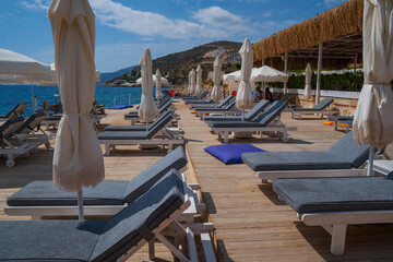 Beach resort, sea summer vacation concept. Lounge wooden sunbeds with umbrellas. A row of sunbeds...