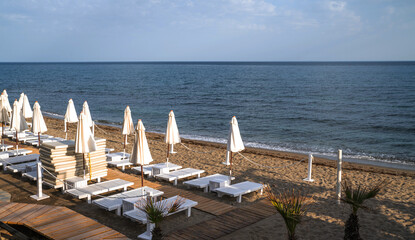 Beach resort, sea summer vacation concept. Lounge wooden sunbeds with umbrellas. A row of sunbeds...
