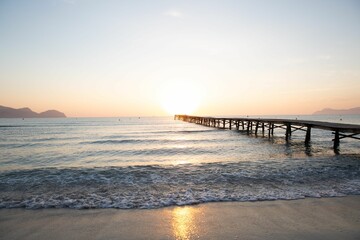 Obraz premium a sunset is shown with waves rolling in and a pier