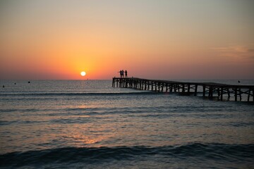 a sunset is shown with waves rolling in and a pier