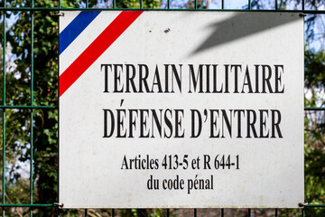 Close-up of a no trespassing sign with a fence background. Sign prohibitionof entry on a military field in France.  A sign military ground-No entry. Military ground defense to enter, - obrazy, fototapety, plakaty