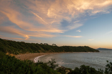 Scenic beach landscape featuring a shoreline of large, jagged rocks at sunset.