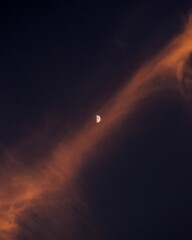 Moon sets behind a backdrop of wispy clouds in a peaceful night sky