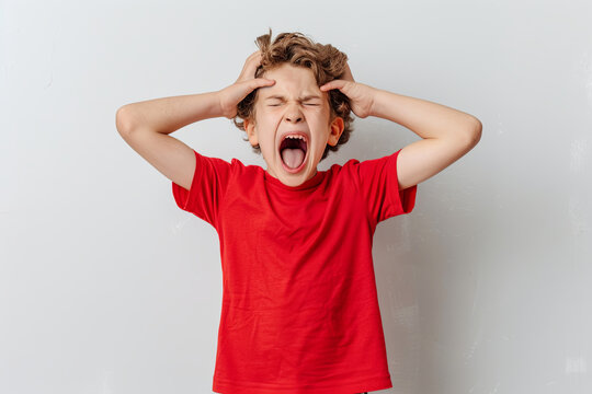 Angry boy in red tee holding his head shouting angrily
