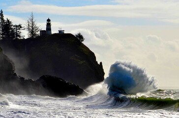 Ocean waves crashing along the Washington coast during stormy weather with the North Head Lighthouse © Wirestock