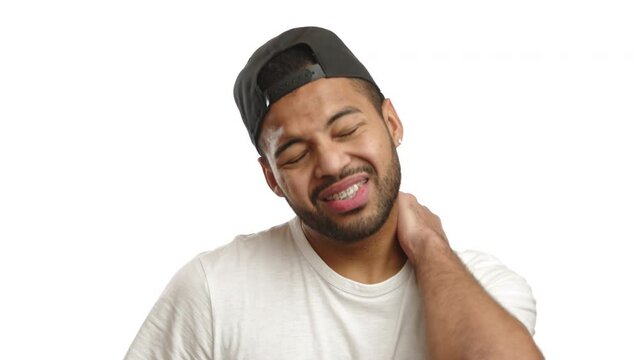 A grimacing man holds his neck, signaling neck pain or discomfort, against a simplistic white background, his face expressing the ache. Camera 8K RAW.