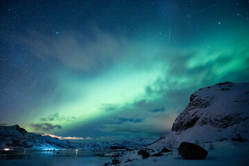 Aurora borealis, Northern lights glowing over snowy mountain on arctic ocean at Lofoten Islands - 773153800