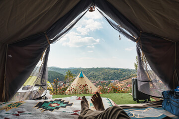 Male traveler relaxing and enjoying with the mountain, local village view inside camping tent on vacation - 773154045