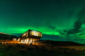 Aurora borealis, Northern lights glowing over luxury hotel on volcanic wilderness in winter at Iceland - 773154252