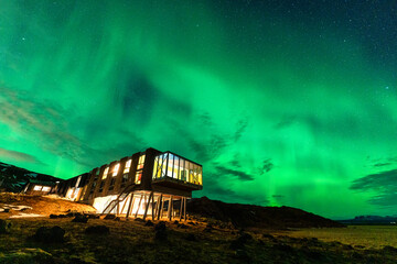 Aurora borealis, Northern lights glowing over luxury hotel on volcanic wilderness in winter at Iceland - 773154412