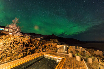 Aurora borealis, Northern lights over hot spring pool in luxury hotel at night