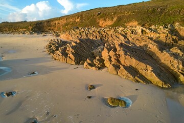 a sandy beach with lots of rocks and water running towards it