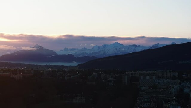 Panoramic view of Apls above city at sunrise. Snowcapped mountain ridge against clouds in sky. Geneva, Switzerland