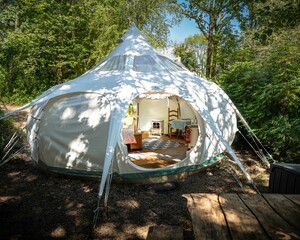 a teepee tent sitting on top of a field near trees