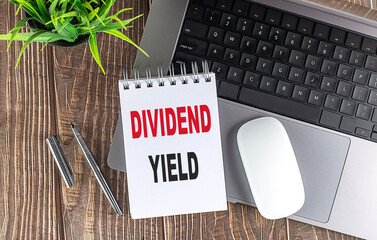 DIVIDEND YIELD text on notebook with laptop, mouse and pen
